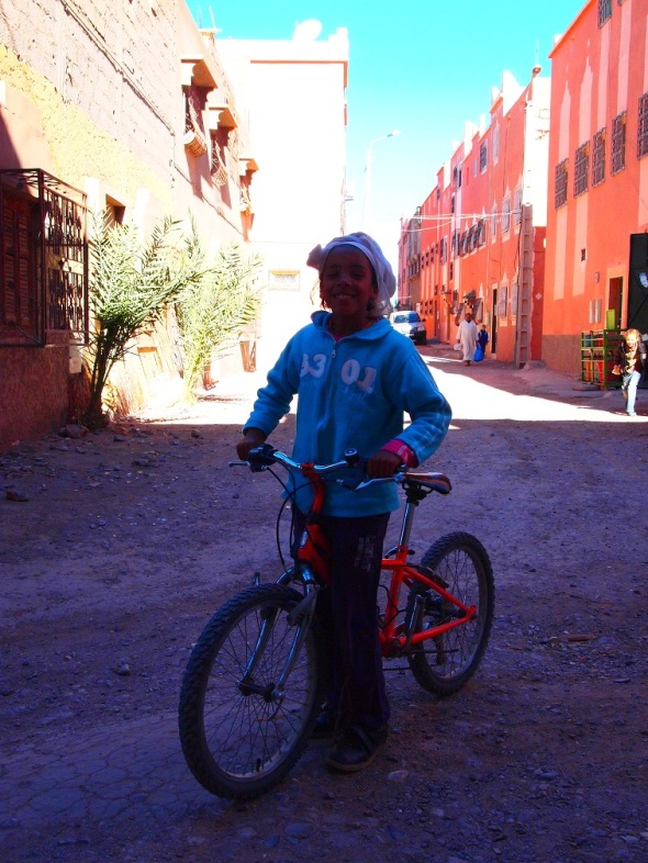 Girl in Ouarzazate showing her red bicycle